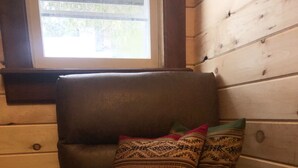Een leren fauteuil met patroon kussens in een kamer met houten wanden en een raam.