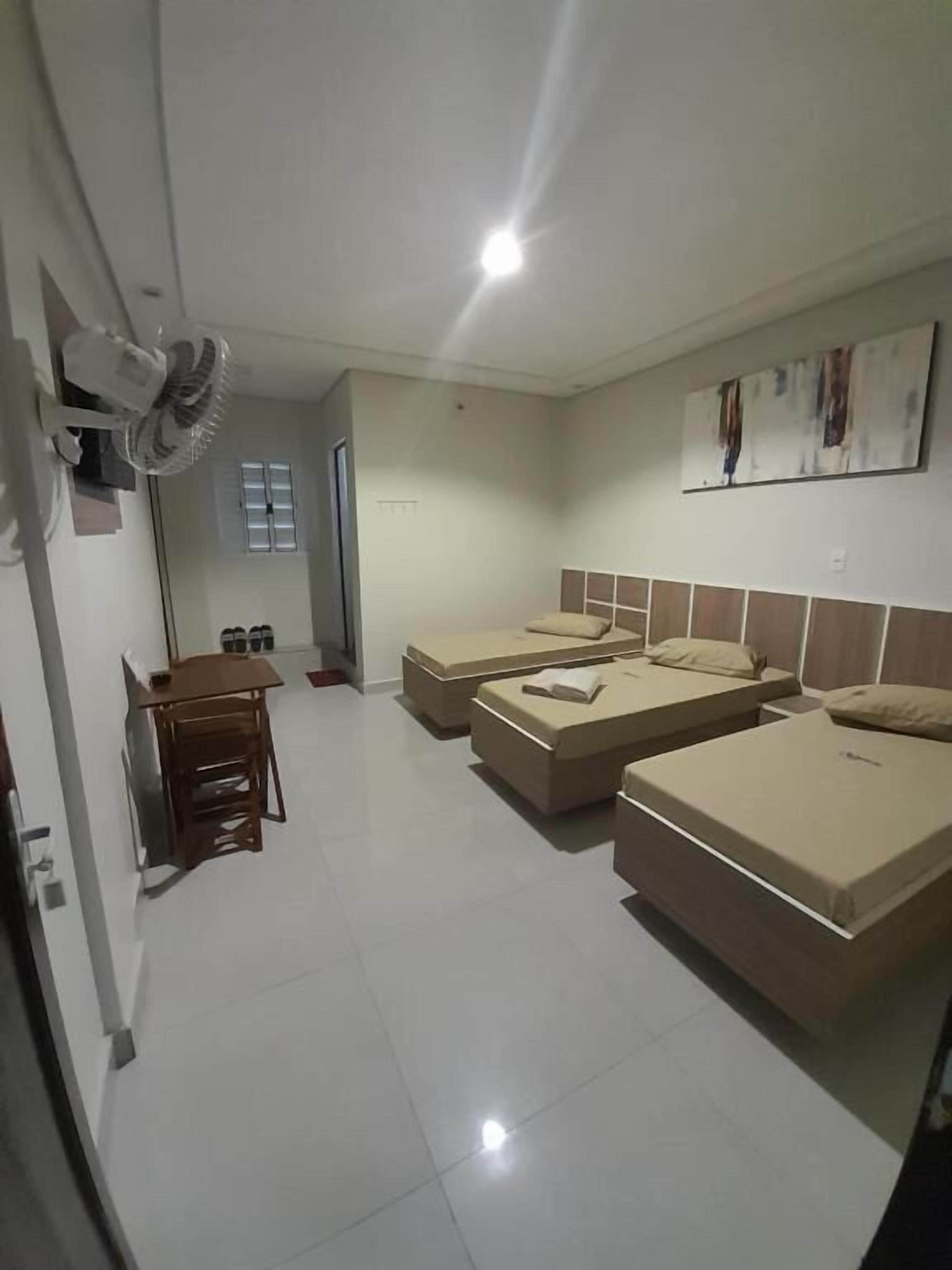A hotel room with two beds, a desk, and a chair.