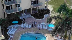 Une piscine sur le toit, dotée de plusieurs niveaux de balcons, de chaises longues et de parasols.