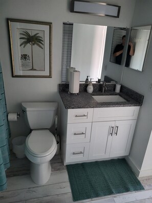 Et badeværelse med toilet, vask og skab.
