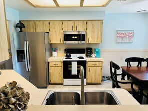 Una cocina moderna con electrodomésticos de acero inoxidable, armarios de madera y un comedor con mesa y sillas.