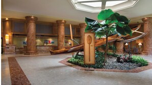 Un vestíbul amb una jardiniera central, columnes i una recepció.