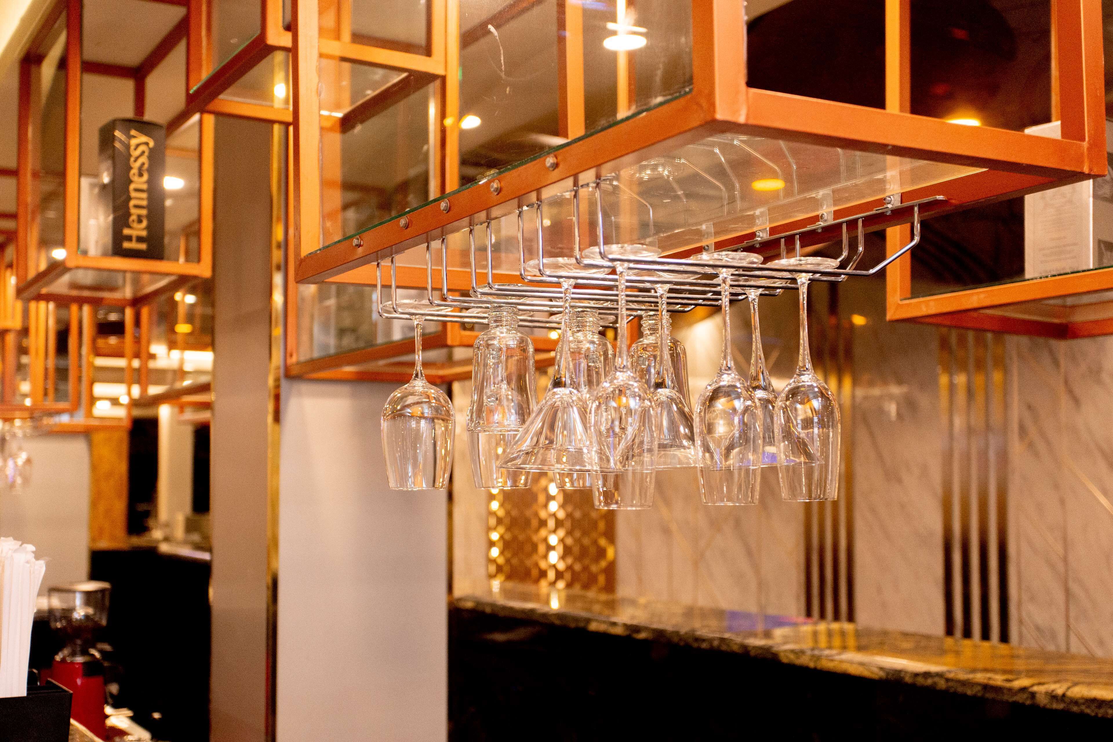 Una zona de bar con un soporte para copas de vino y un cartel que dice "Hennessy".