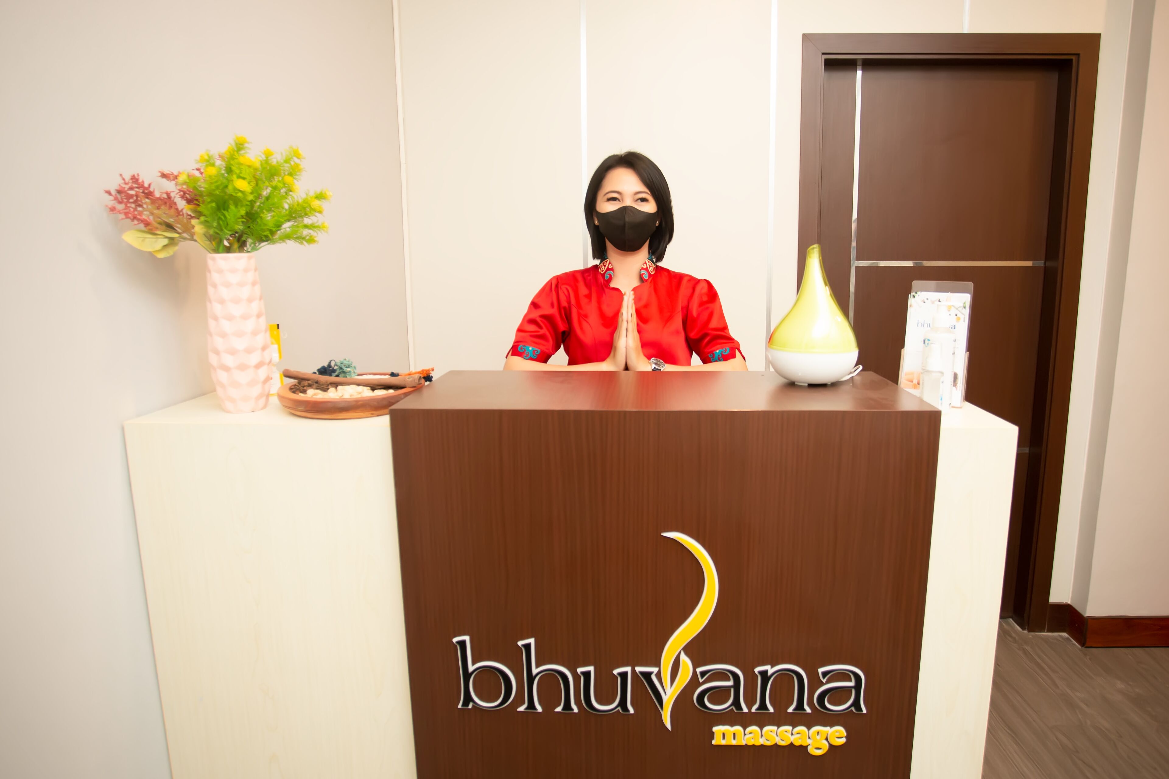 Un comptoir d’accueil orné d’un logo sur lequel on peut lire « bhuvana massage ».