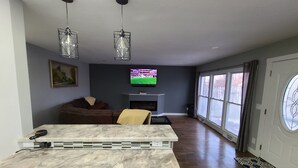 Una sala de estar moderna con una mesa de centro de mármol, un televisor de pantalla plana, chimenea y ventanas amplias.
