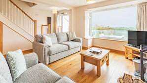 A living room with a sofa, a coffee table, a TV, and a window with a view. - 4 bedroom accommodation in Keswick (Keswick)
