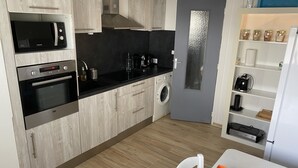 Eine moderne Küche mit integrierten Geräten, einer Waschmaschine und einem Essbereich mit Tisch und Stühlen.