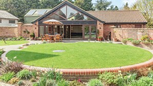 A modern house with a patio, a dining area, and a brick wall. - Cedar Barn - UKC5406 (Banham)