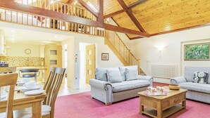 A spacious living area with a high ceiling, wooden beams, a staircase, and a dining area with a table and chairs. - Cedar Barn - UKC5406 (Banham)