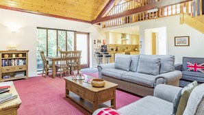A spacious living area with a high ceiling, a dining table with chairs, a sofa, and a bookshelf. - Cedar Barn - UKC5406 (Banham)