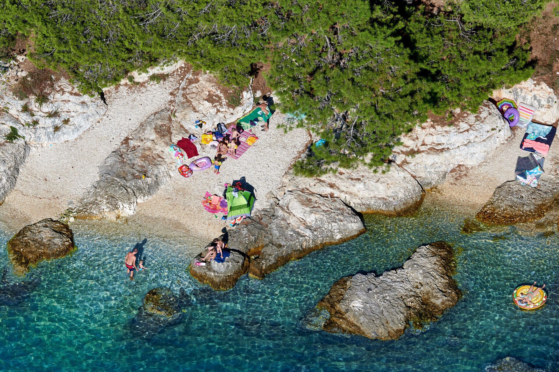 A beach with clear water, rocky formations, and people relaxing.