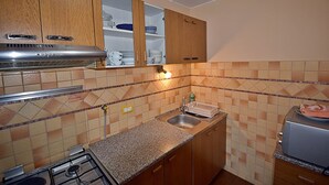A kitchen with wooden cabinets, a gas stove, a sink, and a toaster.