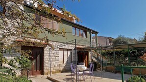 A two-story house with a patio area featuring outdoor furniture.