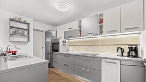 A modern kitchen with grey cabinets, a stainless steel refrigerator, a built-in oven, and a coffee maker. - Apartment Pineta close to the Beach (Medulin)