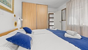 A hotel room with a large bed, a wardrobe, a bathroom, and a painting on the wall. - Apartment Pineta close to the Beach (Medulin)