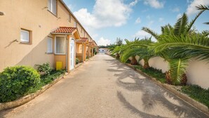A narrow street lined with buildings, palm trees, and a clear sky. - Charming Pool Apartment Liznjan - Buneta (Ližnjan)