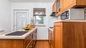 A compact kitchen with wooden cabinets, a microwave, and a window with blinds. - Charming Pool Apartment Liznjan - Buneta (Ližnjan)