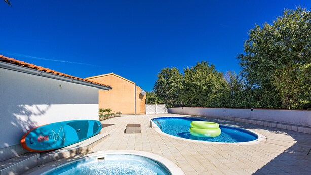 A swimming pool area with two pools, one with a green inflatable ring and another with a blue inflatable ring. - Charming Pool Apartment Liznjan - Buneta (Ližnjan)