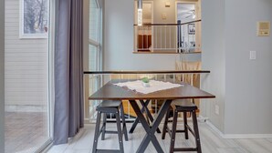 A dining area with a table, four stools, and a potted plant.