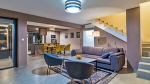 Un salon moderne avec un canapé, des fauteuils, une table basse et un escalier.