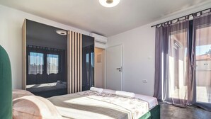 Une chambre moderne avec un lit, une grande fenêtre avec des rideaux et un appareil de climatisation.