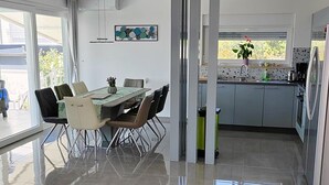 Een moderne keuken met een eetgedeelte, voorzien van een groot raam, een spoelbak en een koelkast.