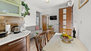 A compact kitchen with a microwave, coffee maker, and a dining area with a table set for a meal. - Apartment Neda with Magnificent sea View (Rabac)