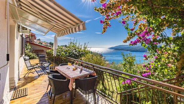 A balcony with a wooden table and chairs, overlooking a scenic view of the sea and mountains. - Apartment Neda with Magnificent sea View (Rabac)
