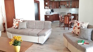 A living room with a sofa, a coffee table with a vase of flowers, and a dining area with chairs and a table. - Apartment Tina with Terrace & Lovely Garden (Pula)
