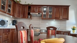 A modern kitchen with wooden cabinets, a stainless steel stove, and a dining table set with fruit. - Apartment Tina with Terrace & Lovely Garden (Pula)