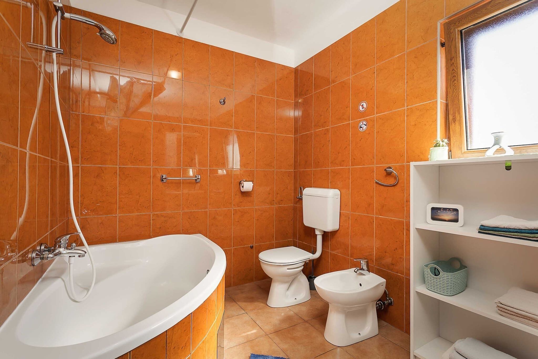 Une salle de bain équipée d’une baignoire, de toilettes, d’un bidet et d’une étagère avec des serviettes.