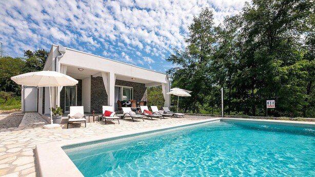 A modern poolside area with a stone-tiled deck, lounge chairs, and umbrellas. - Villa Sofia with Private Pool (Santalezi)