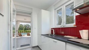 A modern kitchen with white cabinets, a red backsplash, and a large window. - Villa Sofia with Private Pool (Santalezi)