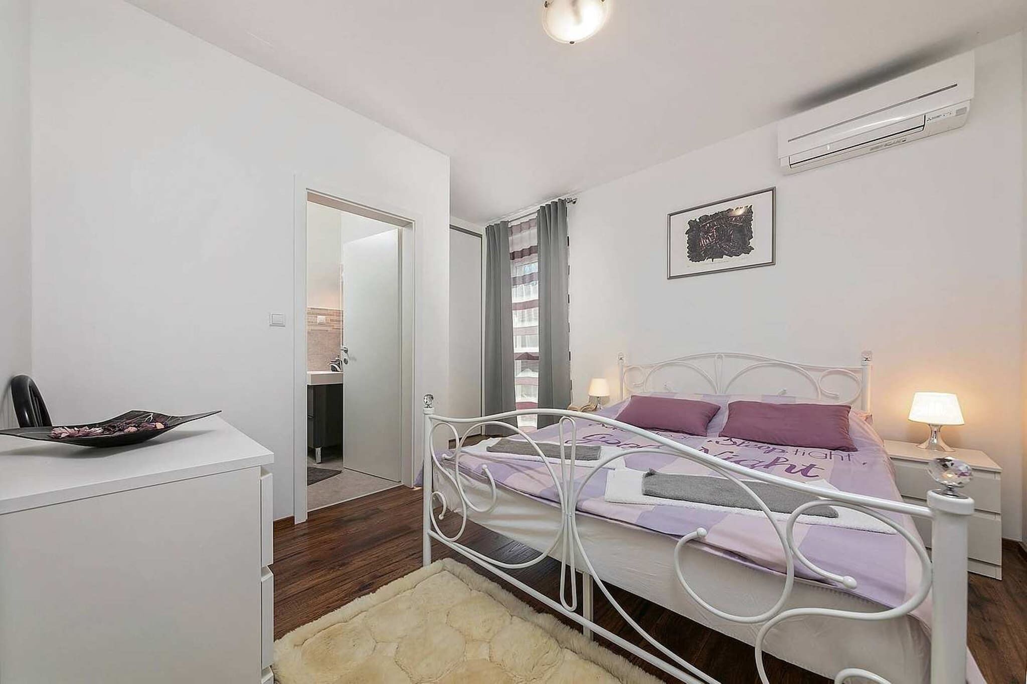 A bedroom with a bed, bedside tables, a desk, and a chair.