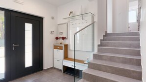 A modern interior with a dark door, a glass staircase, and a white vanity with a mirror.