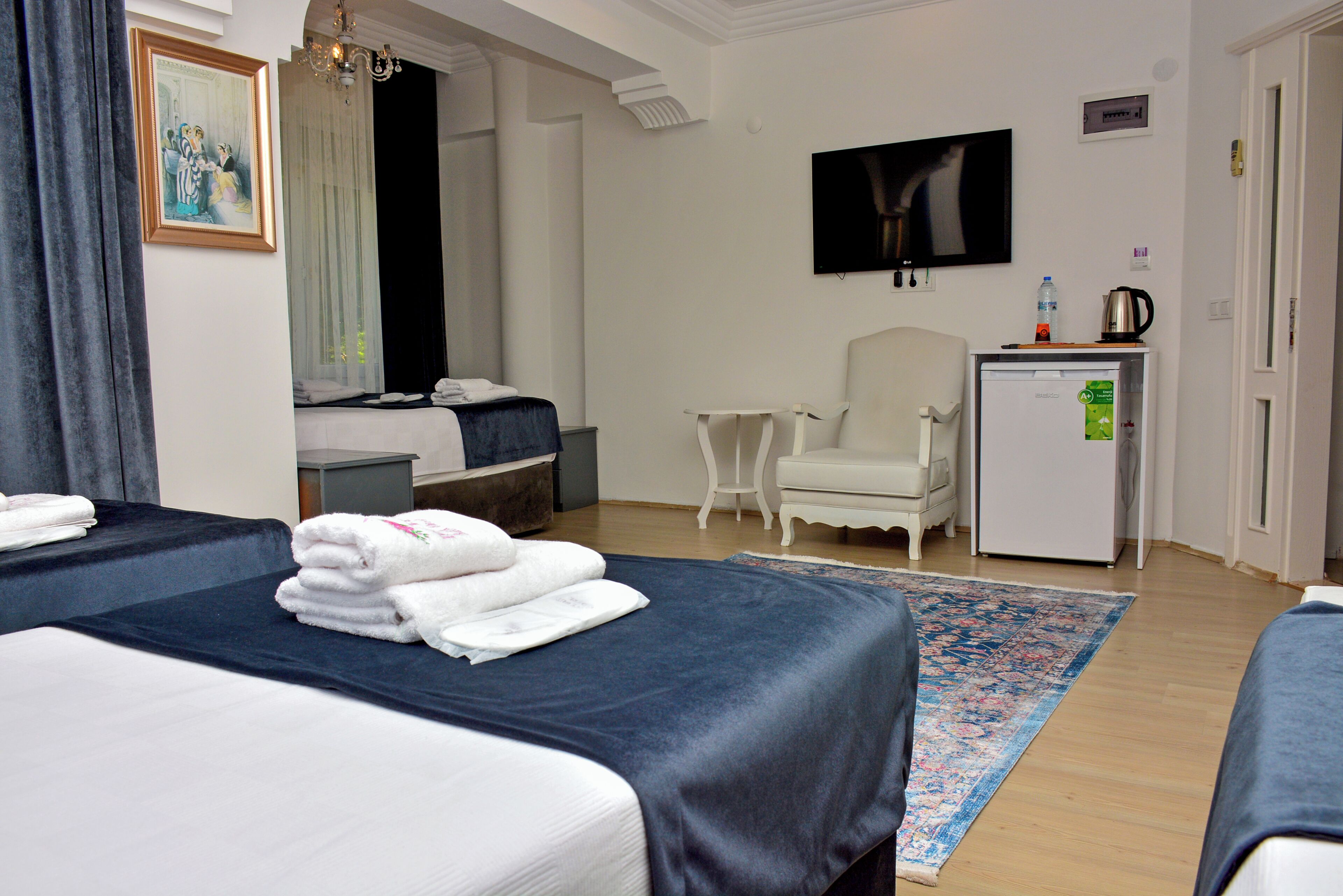 Een hotelkamer met twee bedden, een klein bureau, een stoel, een televisie en een koelkast.