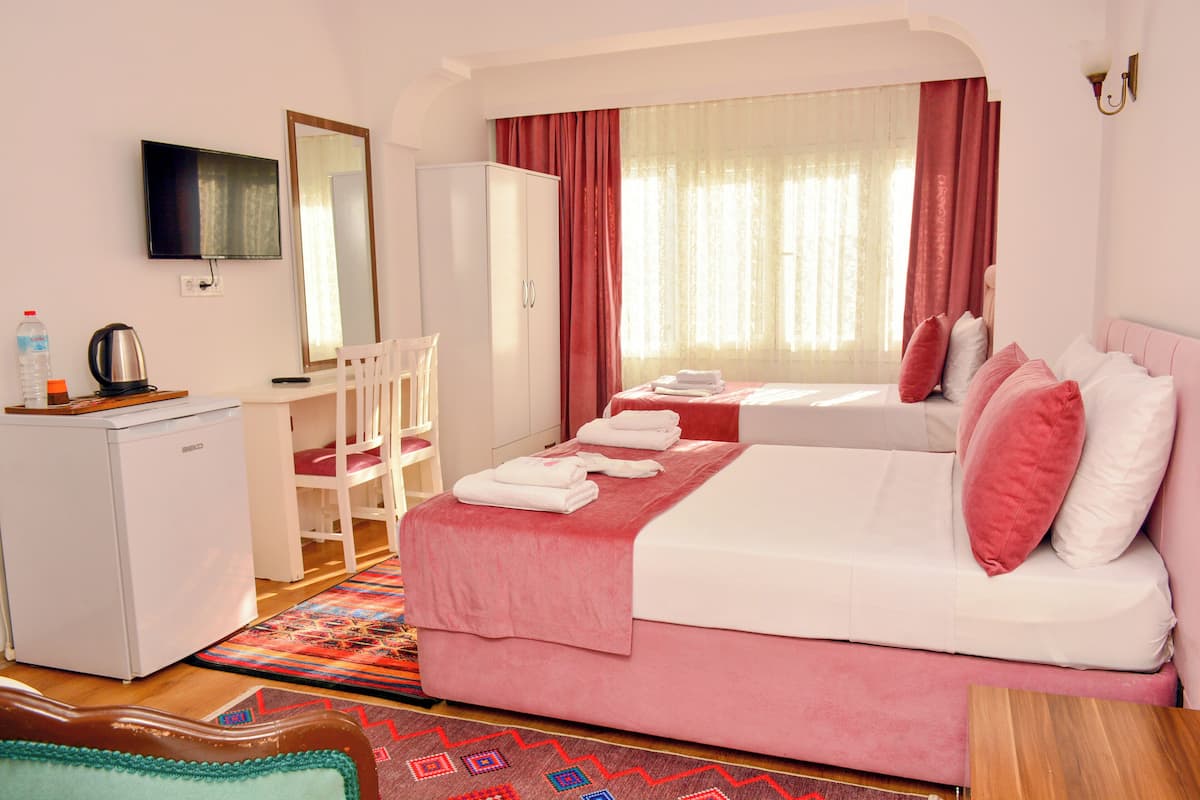 A hotel room with a bed, a desk, a chair, a television, and a wardrobe.