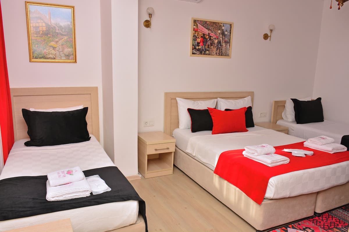 A hotel room with two beds, a nightstand, and artwork on the walls.
