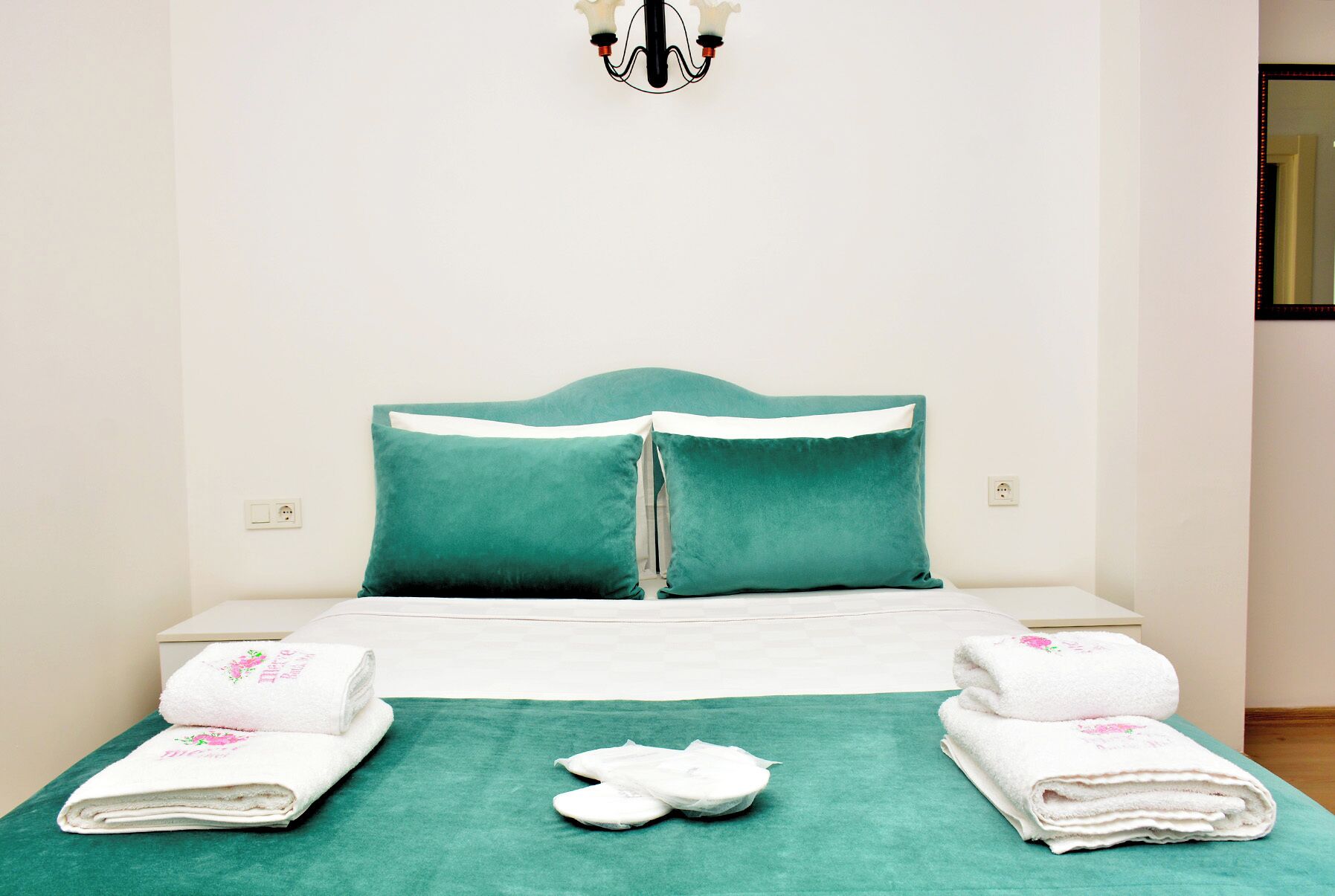 Una cama bien hecha con ropa de cama color turquesa, almohadas blancas y una manta color turquesa.
