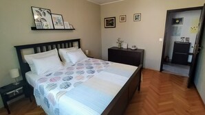 Een keurig opgemaakt slaapkamer met een bed, nachtkastjes en een klein bureau.