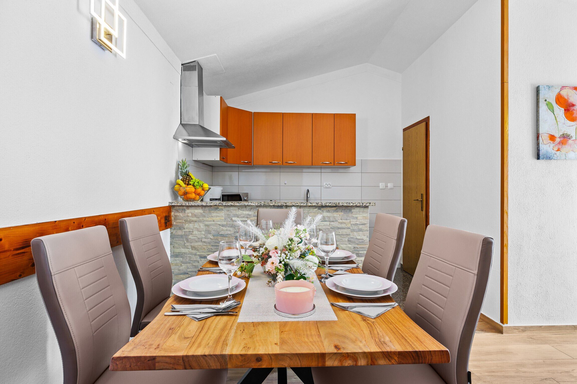 A dining area with a wooden table, beige chairs, and a pink centerpiece.
