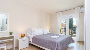 Une chambre avec un lit, une table de chevet, une lampe et une vue sur le balcon extérieur.