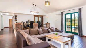A spacious living area with a sectional sofa, a wooden coffee table, and a dining area with a brick fireplace. - Villa Boris with Private Pool (Vodnjan)