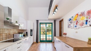 A modern kitchen with white cabinets, a wooden countertop, and a view to the outside. - Villa Boris with Private Pool (Vodnjan)