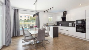 A modern kitchen with white cabinets, a black countertop, and a built-in oven. - Holiday Home Greta with Private Pool (Salakovci)