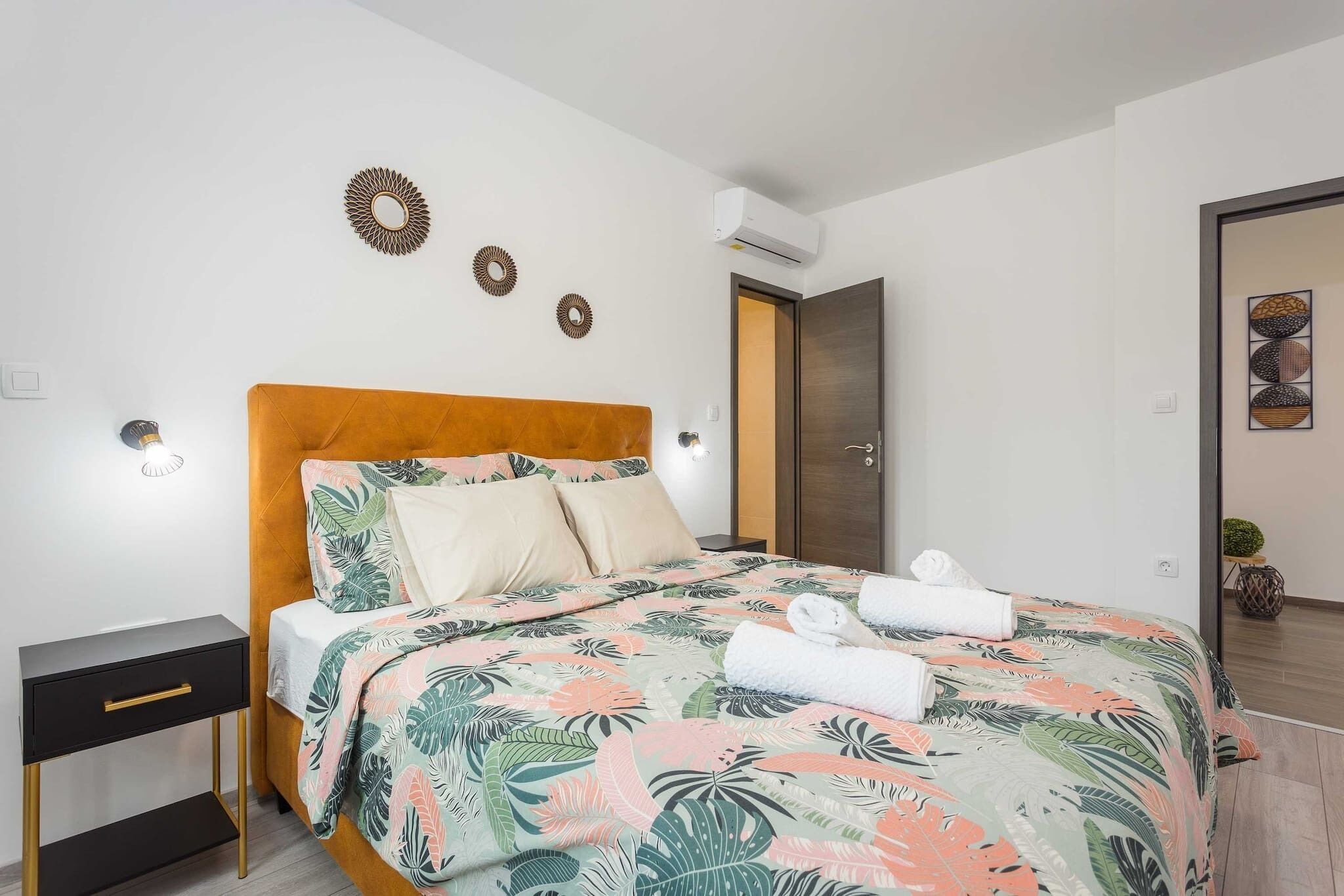 Ein Schlafzimmer mit Bett, Nachttisch, Wanddekoration und Klimaanlage.