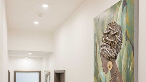 A hallway with a wooden floor, a painting of a person with a headpiece, and a door at the end. - Holiday Home Greta with Private Pool (Salakovci)