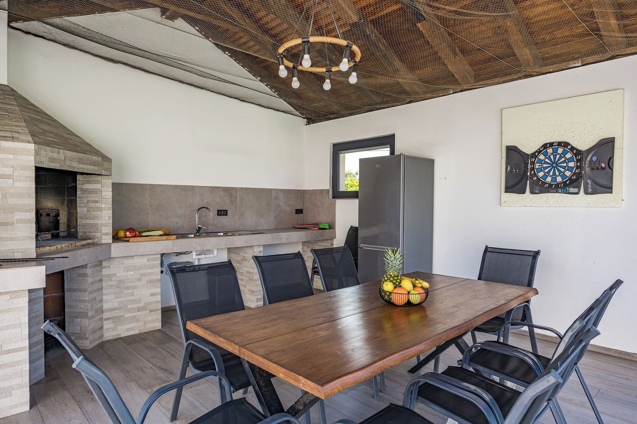 A modern kitchen with a built-in oven, a refrigerator, and a dining area with a wooden table and chairs.