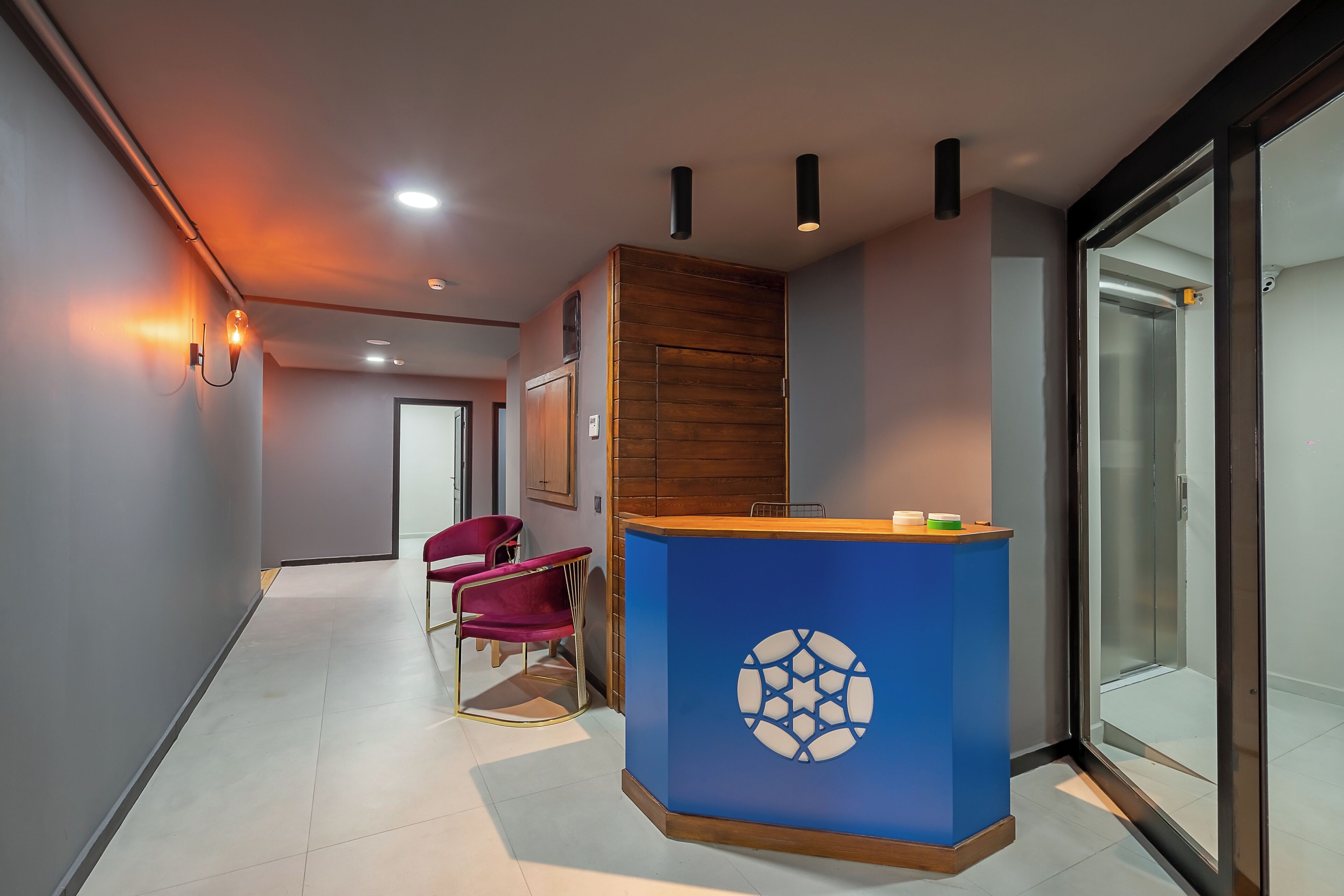 Un área de recepción con un mostrador azul, un gabinete de madera y una silla roja.