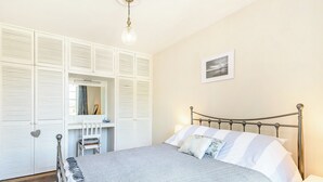A bedroom with a bed, a bedside table, a mirror, and a wardrobe. - 2 bedroom accommodation in Berwick Upon Tweed (Berwick Upon Tweed)